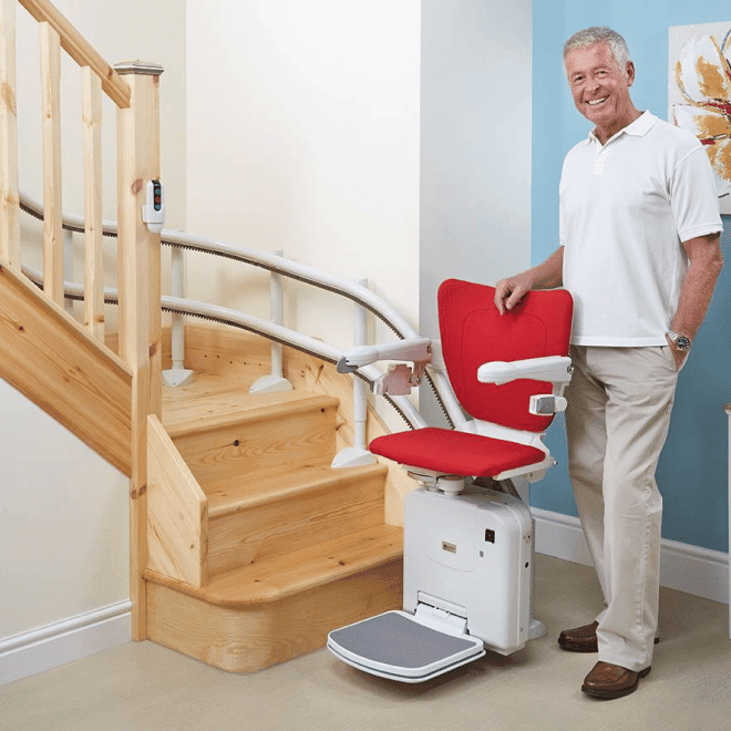 Homme d'âge mûr avec fauteuil monte-escalier au pied d'un escalier