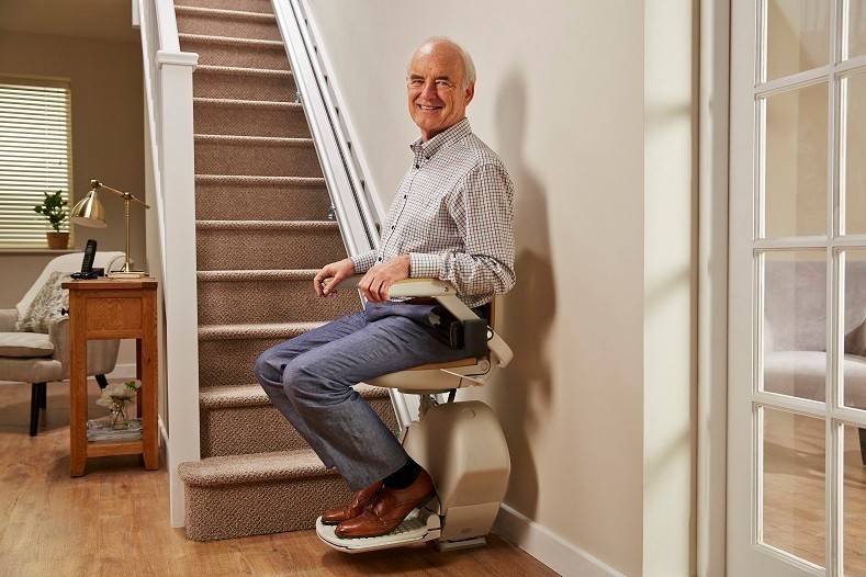 Homme âgé dans fauteuil monte-escalier électrique couloir