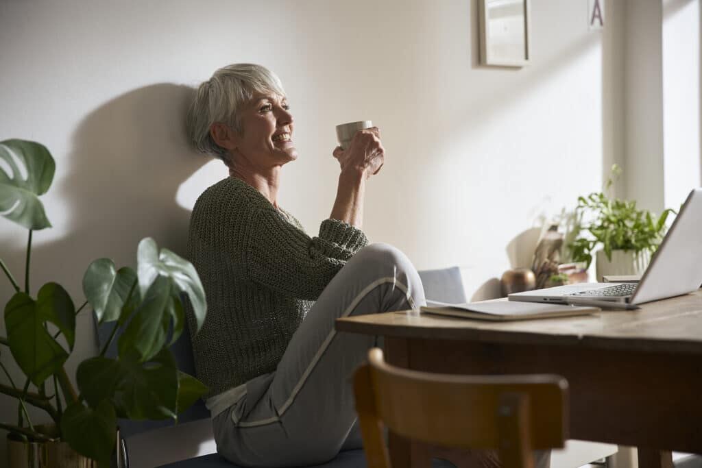 Femme de plus de 60 ans souriante buvant un thé Prima Vital — photo studio